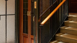 Una puerta de madera con una celosía de metal y un pasamanos de madera al lado de una escalera.