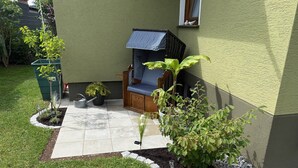 A patio area with a seating arrangement, a small garden, and a building with a green exterior. - Comfortable vacation apartment in the center of Schleiden National Park (Schleiden)