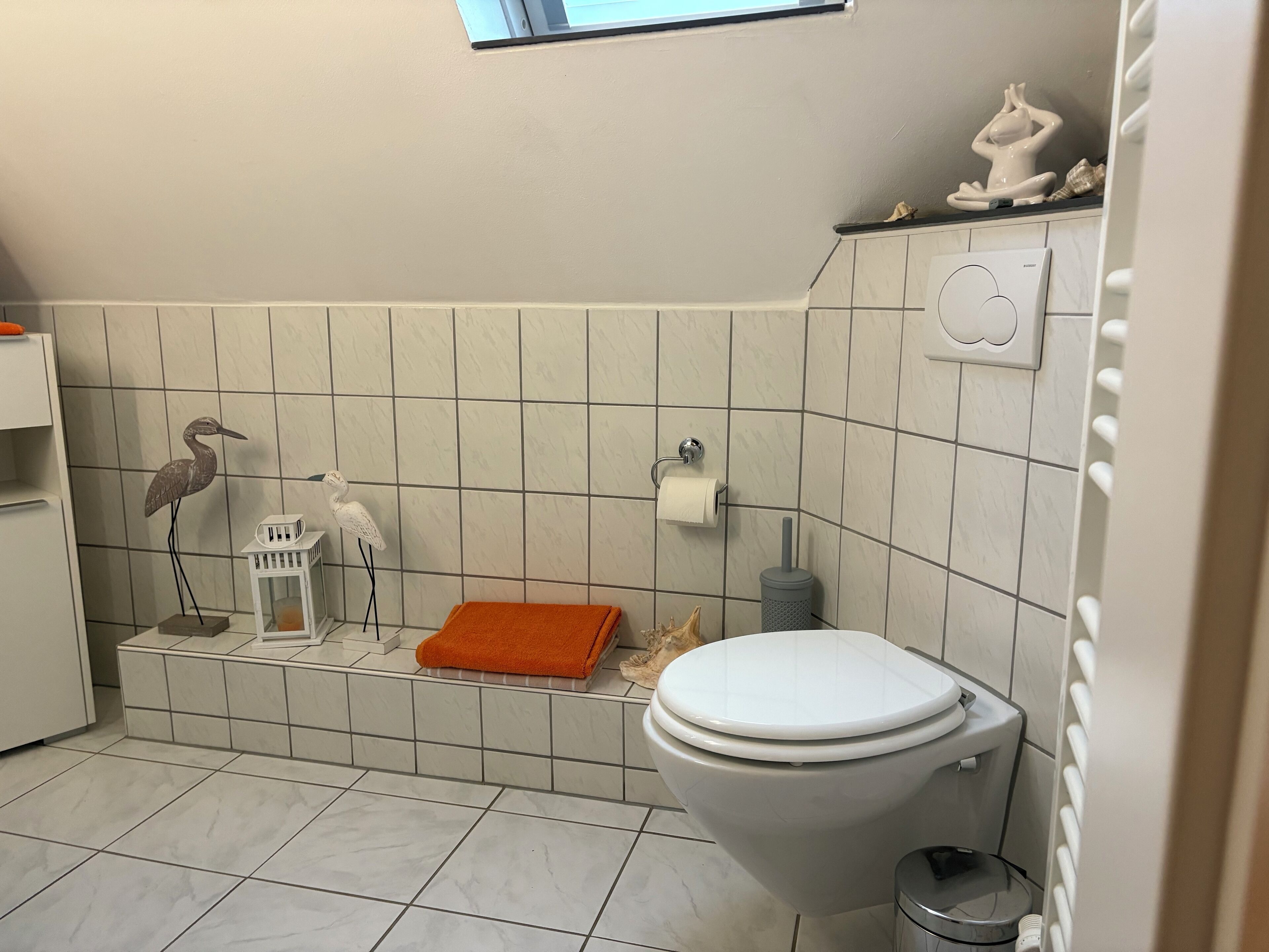 Ein Badezimmer mit Toilette, Waschbecken, Handtuchhalter und einer dekorativen Vogelstatue.