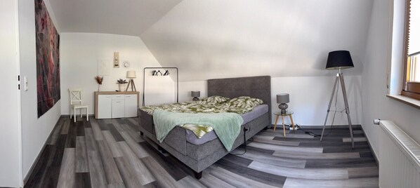 Een slaapkamer met een bed, nachtkastjes, een lamp, een vloerlamp en een radiator.