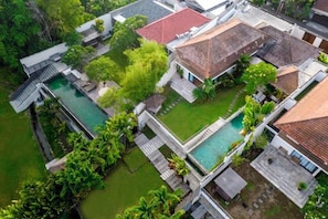 A modern residential complex with multiple houses, each featuring a swimming pool and surrounded by lush greenery.