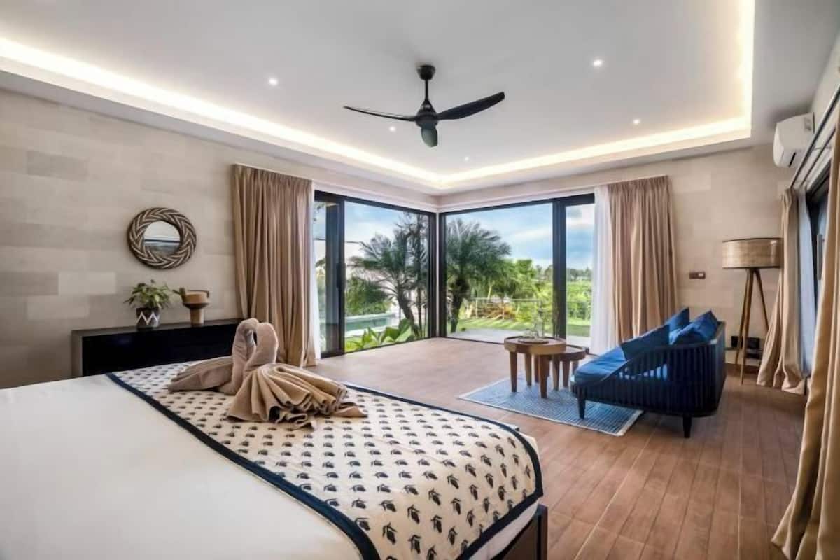 Une chambre d’hôtel moderne, équipée d’un lit, d’un canapé, d’un ventilateur de plafond et offrant une vue sur l’extérieur.