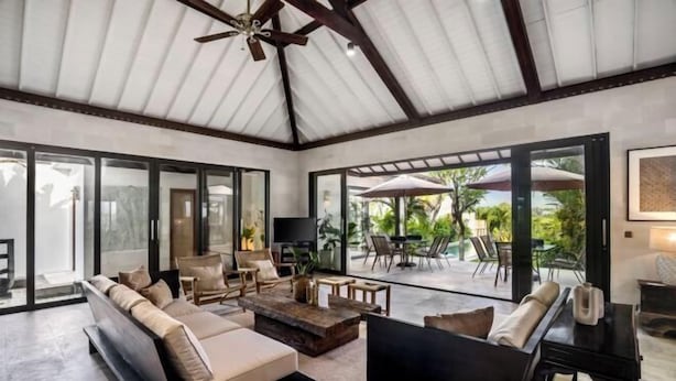 Amplia sala de estar con un sofá grande, una mesa de centro y un televisor. Ofrece múltiples opciones de asientos y vista al área del patio exterior.