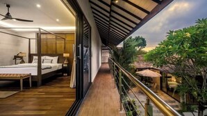 Una habitación de hotel moderna con balcón, suelo de madera y vistas al entorno verde.