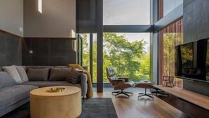 A modern living room with a sofa, a coffee table, and a fireplace. - Rinzan Chalet | 3BR Soga Chalet | Onsen-Style Bath & Yotei View (Rinzan)