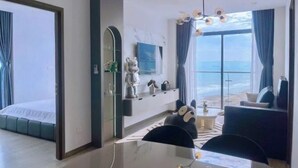 A modern hotel room with a large window, a dining area, and a sofa. - Bap's House - CSJ Apartment Vung Tau (Vung Tau)