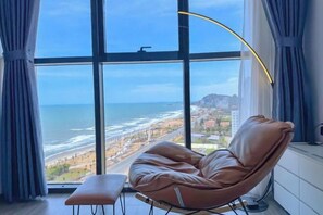 Una habitación con un ventanal grande, un sillón de cuero y un pequeño banco.