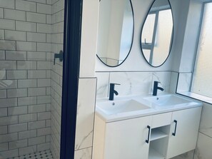 Ett badrum med två handfat, en dusch och ett fönster.