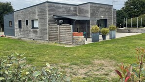 A modern building with a grey facade, a covered entrance, and a brick structure. - Charming gîte in Dragey, at the gateway to the bay for 10 people (Dragey-Ronthon)