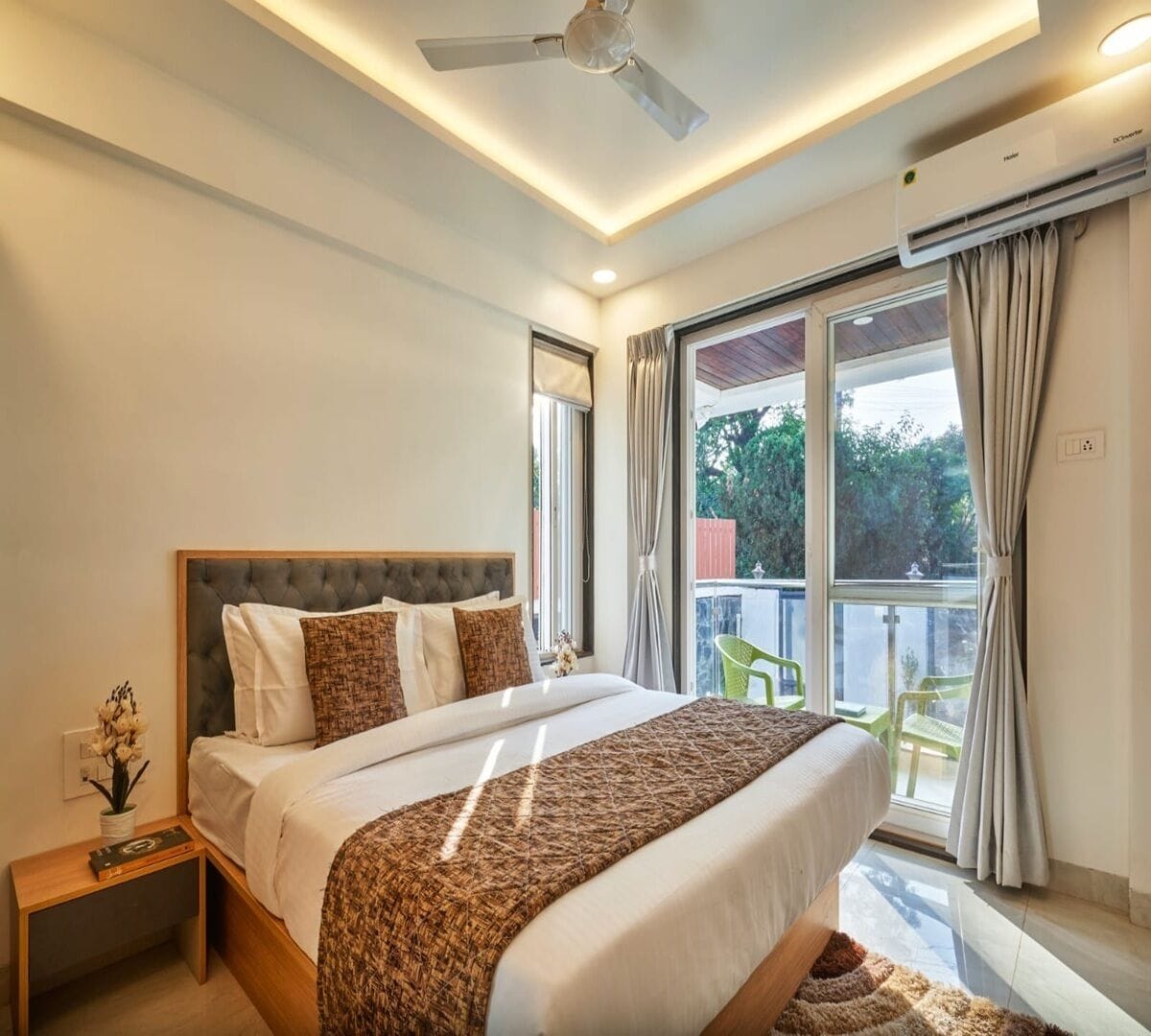 A modern bedroom with a large bed, a ceiling fan, and a view of the outdoors.