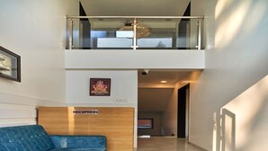 Egy modern szállodai recepció, melynek berendezésében egy kék kanapé, egy recepciós pult és egy üvegkorlátos galéria található, ahonnan a hallra nyílik kilátás.