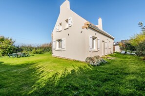 Una casa de un piso con techo inclinado, chimenea y césped bien cuidado.