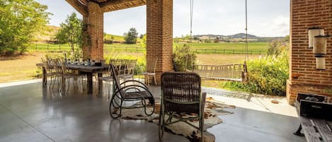 An outdoor patio with a brick wall, a wooden table, and wicker chairs.