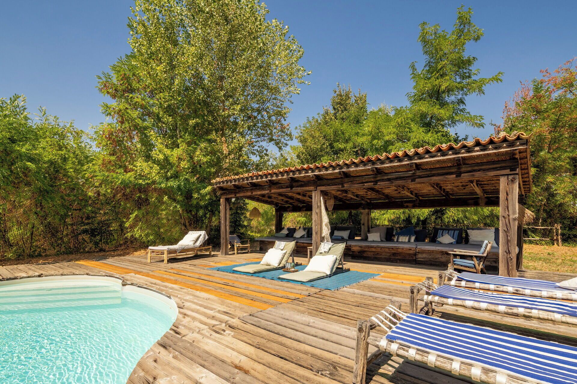 Une terrasse en bois avec des chaises longues et une piscine.