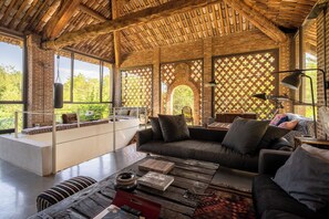 Una sala de estar acogedora con techo de madera, un sofá, una mesa de centro y vistas al exterior.