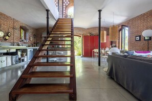 A modern kitchen with a wooden staircase leading to a dining area.