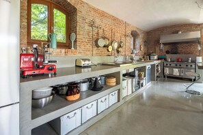A kitchen with a brick wall, a window, and various appliances.