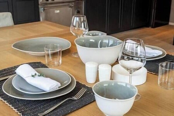Una mesa de comedor dispuesta con platos, tazones, vasos y cubiertos.