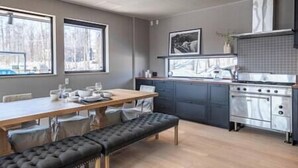 Una cocina moderna con una mesa de comedor y banco, ventanas amplias y una estufa de acero inoxidable.