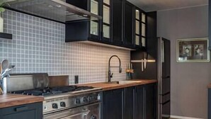 Una cocina moderna con armarios negros, estufa de acero inoxidable y un revoque de azulejos.