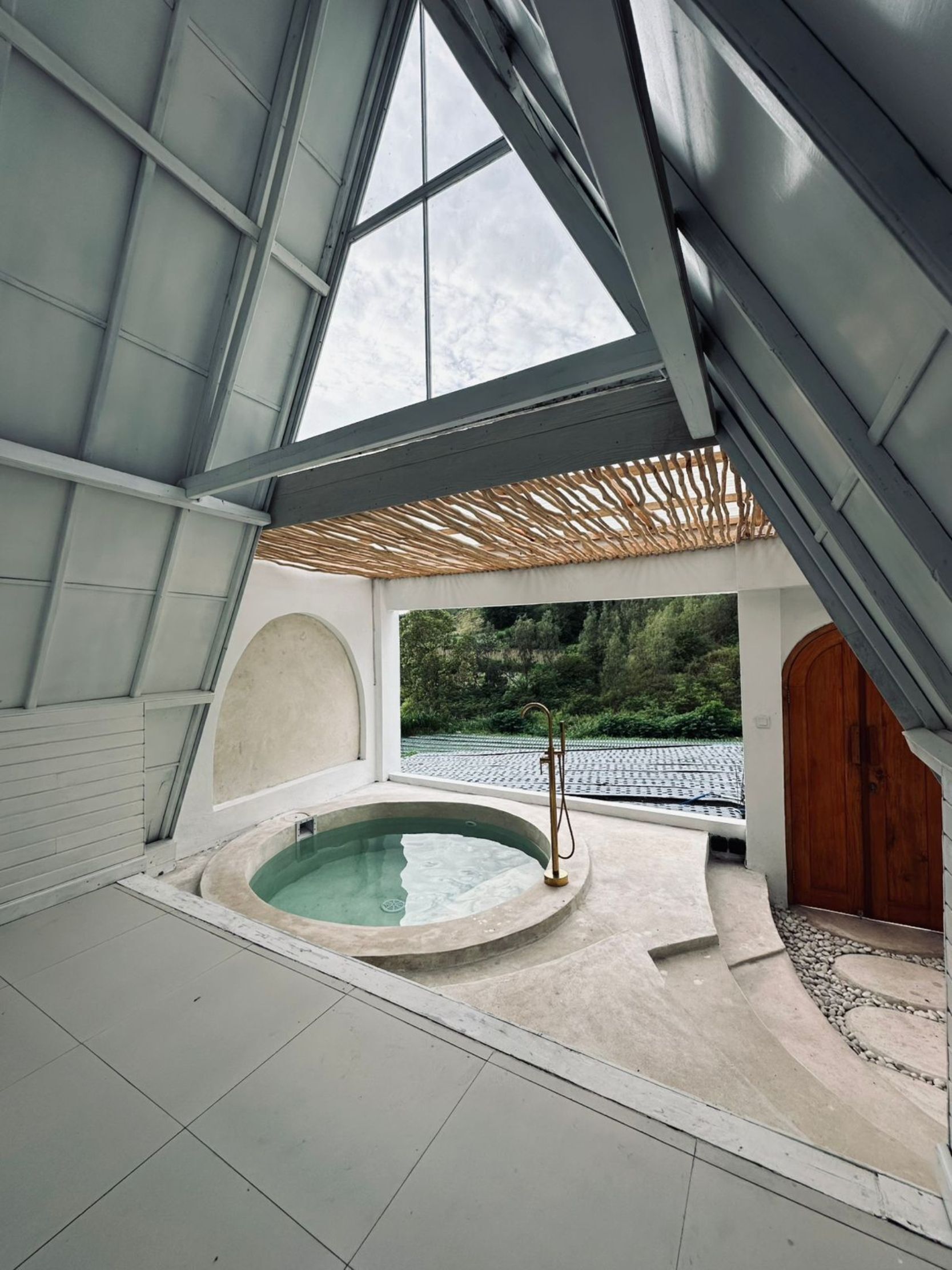 Un espace de bien-être comprenant un jacuzzi, une porte en bois et donnant sur un jardin.