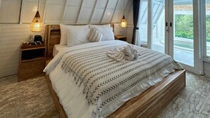 Une chambre spacieuse avec un grand lit, une tête de lit en bois et deux lampes de chevet.