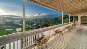 Un espace extérieur abrité doté d’un plancher en bois et de chaises en osier.