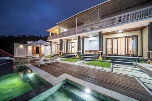 Een modern huis met een zwembad, buitenzitplaatsen en een overdekt terras.