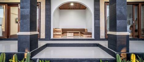 Un vestíbulo moderno con una zona de estar central, pilares de piedra negra y techo de madera.