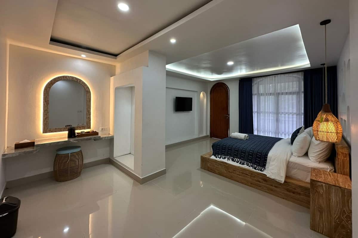 A modern hotel room with a large bed, a TV, a mirror, and a bathroom area.