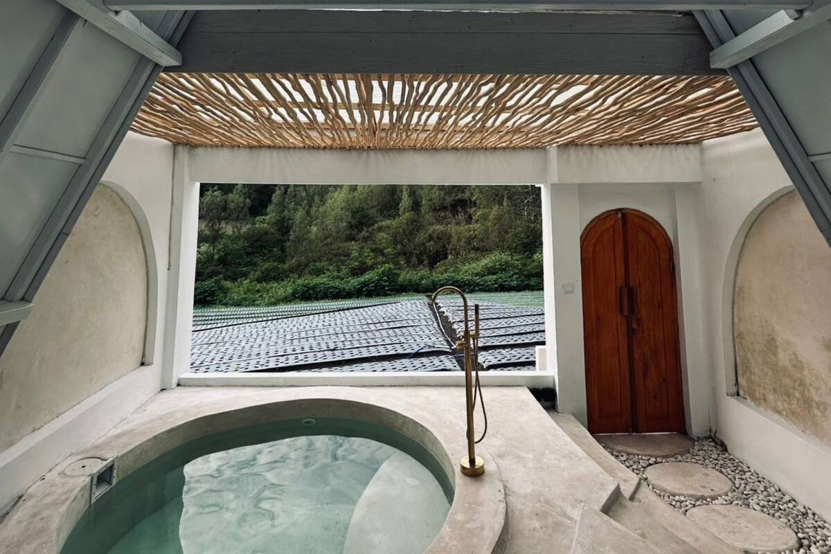 A spa area with a hot tub, a wooden door, and a view of a tiled roof and greenery.