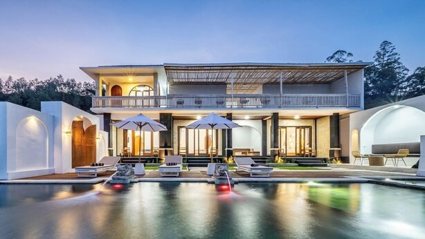 Un bâtiment moderne à deux étages doté d’une piscine, d’un espace extérieur aménagé et d’un balcon couvert.