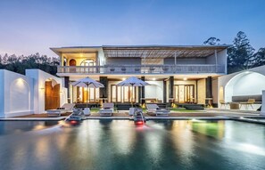 Ein modernes, zweistöckiges Gebäude mit Swimmingpool, Außenbereich und überdachter Terrasse.