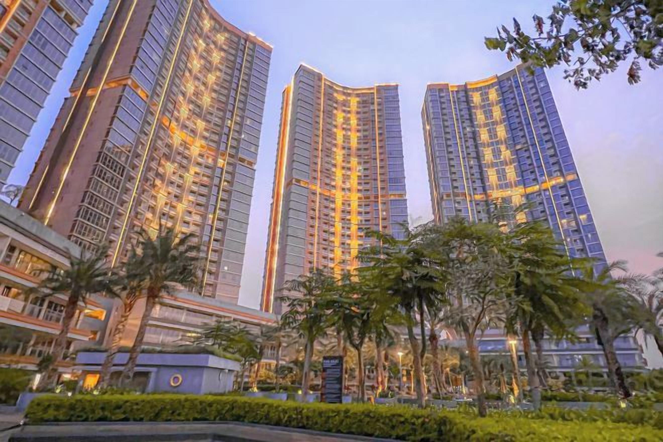 High-rise buildings with a modern architectural design, surrounded by well-maintained greenery.