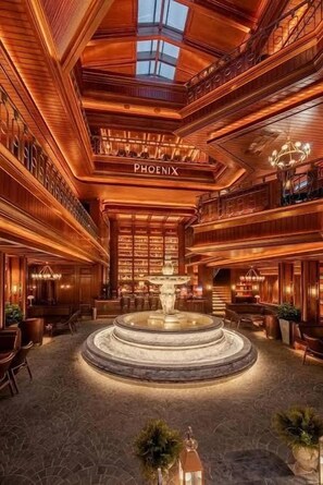 A grand lobby with a central fountain, high ceilings, and a prominent 'PHOENIX' sign. - Gold Coast PIK Apartments by HostJess (North Jakarta)