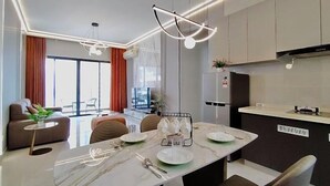 A modern dining area with a marble table, chairs, and a pendant light.