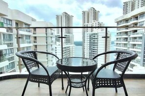A balcony with a round table and two chairs, overlooking high-rise buildings. - Deluxe 3 Bed 3 Bath Apartment (Johor Bahru)
