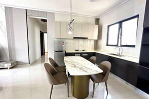 A modern kitchen with a marble countertop, a dining area with chairs, and a large window providing natural light. - Deluxe 3 Bed 3 Bath Apartment (Johor Bahru)