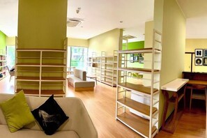 A room with a white sofa, a bookshelf, and a table with a chair. - Deluxe 3 Bed 3 Bath Apartment (Johor Bahru)