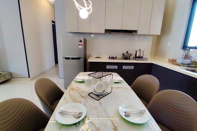 A modern kitchen with a marble countertop, a built-in stove, and a dining area with a marble table and brown chairs.