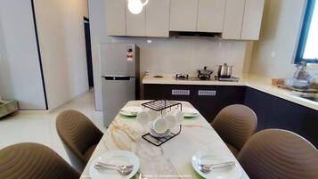 A modern kitchen with a marble countertop, a built-in stove, and a dining area with a marble table and brown chairs.