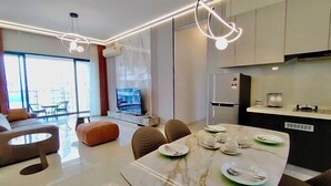 A modern living room with a dining area, large windows, and a kitchen with a built-in oven.
