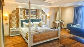 Un lit à baldaquin, une table de chevet, une commode, un canapé bleu et une grande fenêtre avec des rideaux.