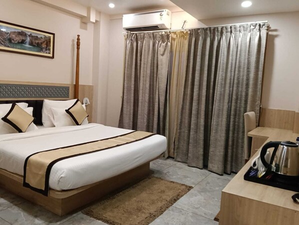 A hotel room with a bed, a desk, an air conditioner, and a curtain. - Golden Retreat (Puri)