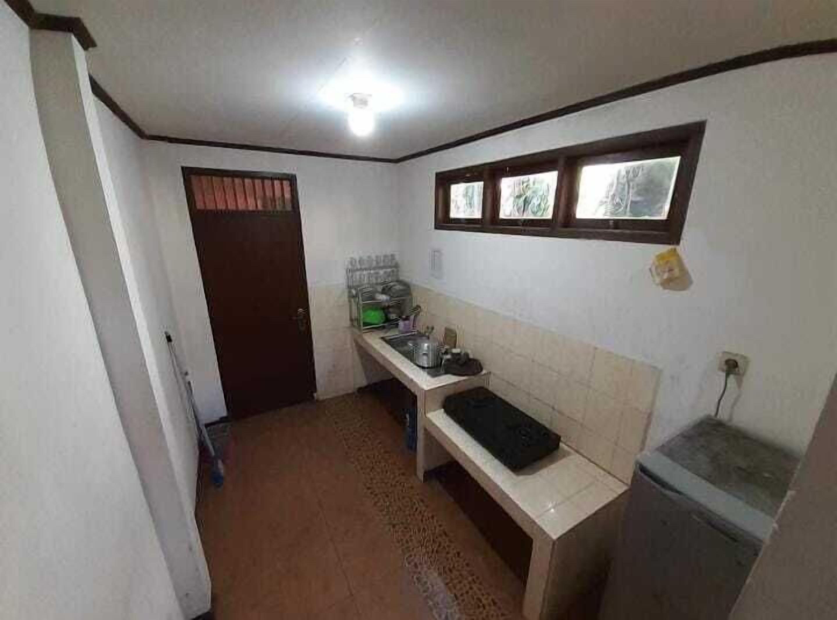 A compact kitchen with a tiled backsplash, a countertop, and a window above the sink.