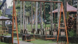 A swing set in a garden with stone steps and tropical plants. - Aquarius Orange Hotel & Villa (Cisarua)