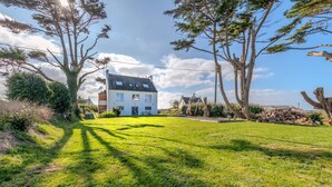 Een tweelaags huis met een groot gazon, een picknicktafel en een tuinhuis.