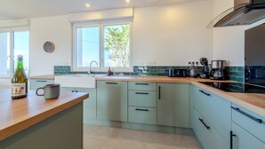 Een moderne keuken met lichtgroene kastjes, een houten aanrecht en een roestvrijstalen afzuigkap.