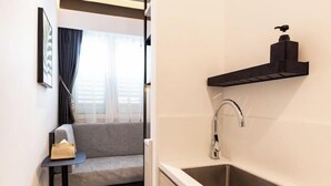 A modern bathroom with a sink, a soap dispenser, and a towel rack.
