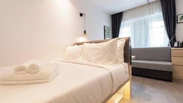 Una habitación de hotel moderna con una cama, un sofá, un escritorio y una lámpara.